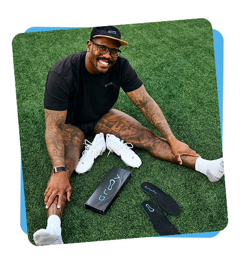 Athlete sitting on turf beside shoes and Groov insoles.